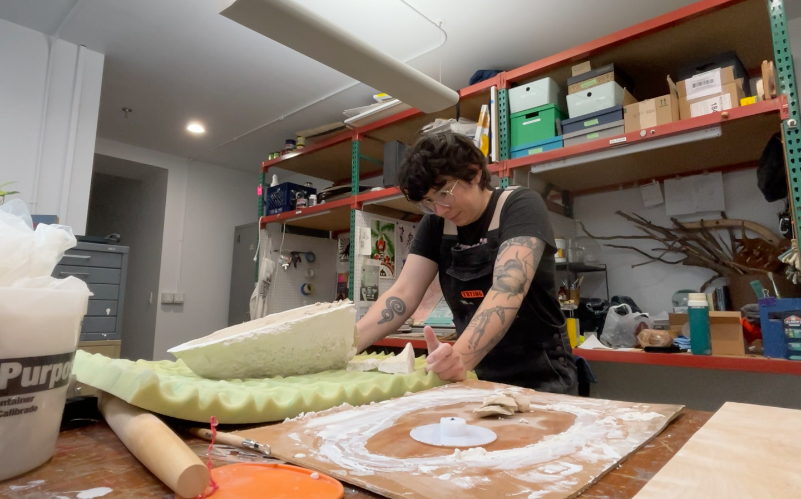 A person looking dejected, staring at a plaster mold that is laying on a piece of green foam.